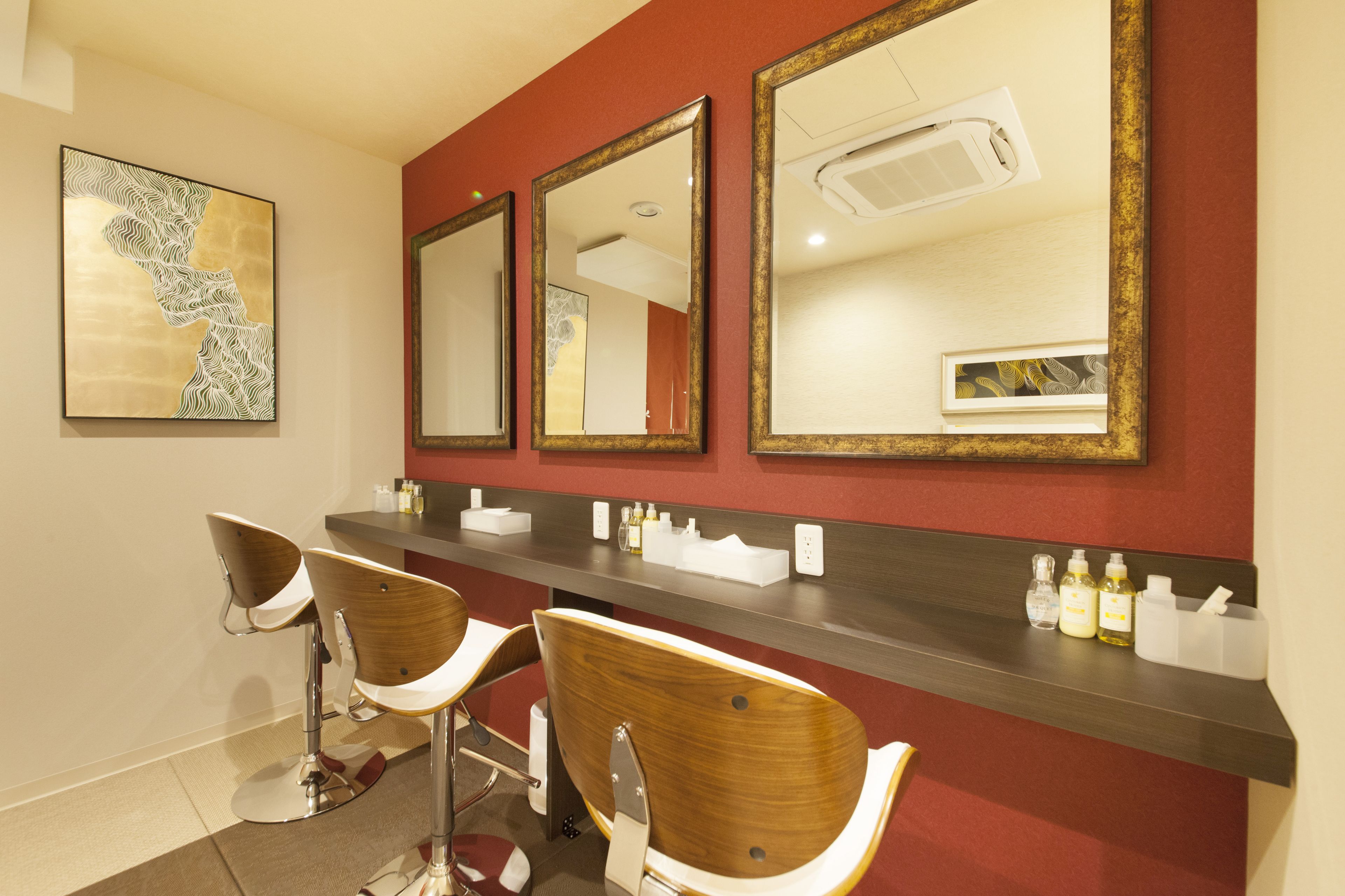 A bathroom with three mirrors, a wooden vanity, and two bar stools.