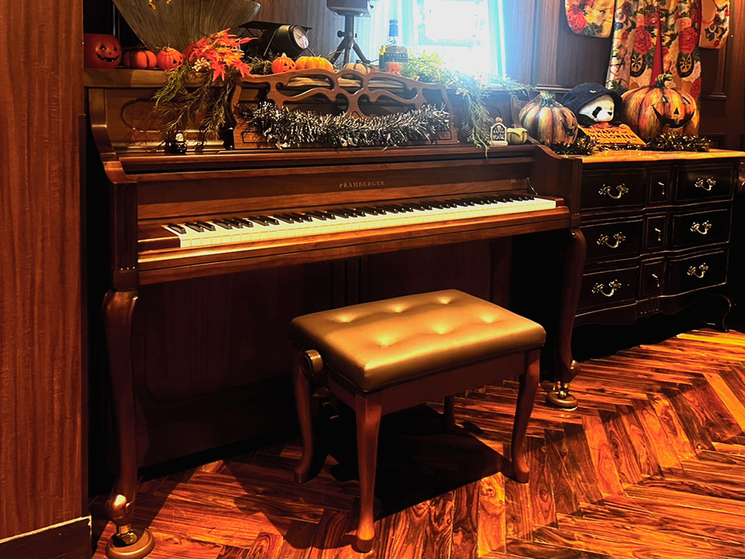 A grand piano with a bench, surrounded by autumn-themed decorations.