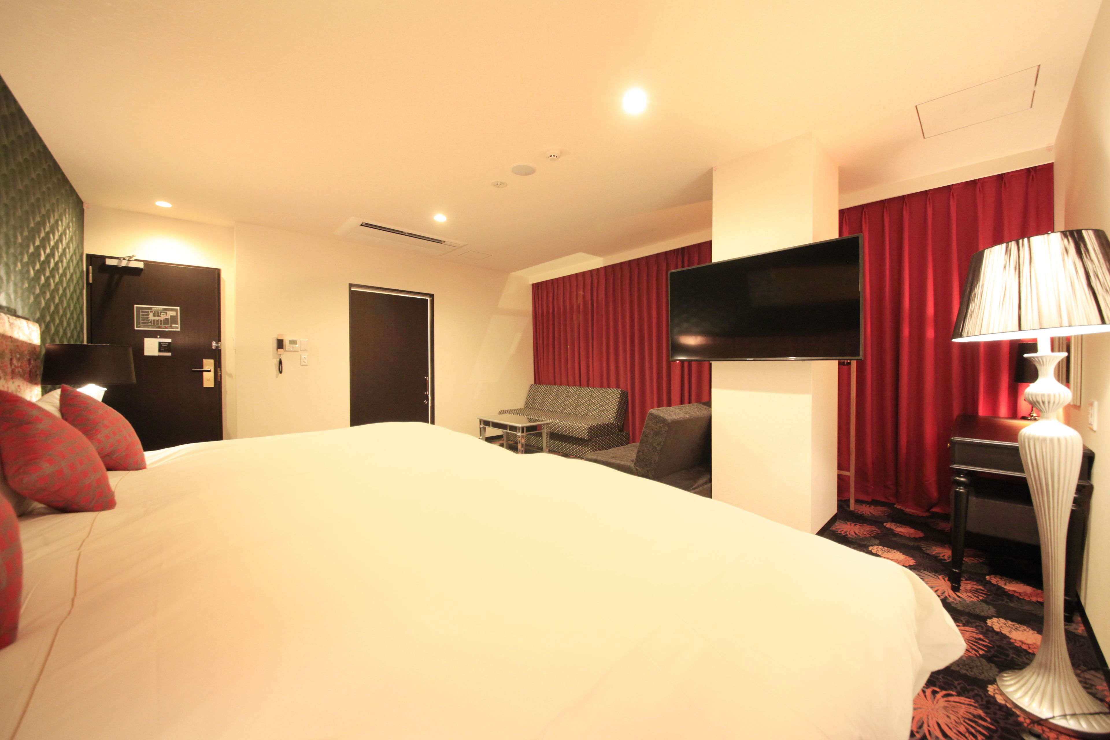 A hotel room with a large bed, a flat-screen TV, a desk, and a chair.