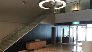 Un hall amplio con una escalera, una mesa de recepción y un ventanal grande.