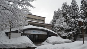 Un edificio con un letrero que dice "AquaAlpine". La nieve cubre el suelo y los árboles.