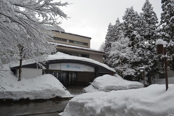 Un edificio con un letrero que dice "AquaAlpine". La nieve cubre el suelo y los árboles.