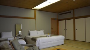 Habitación de hotel con dos camas, una silla, una mesa y un armario.