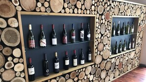 Una exhibición de vinos con botellas en estantes frente a una pared decorada con troncos de madera.