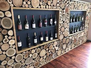 Una exhibición de vinos con botellas en estantes frente a una pared decorada con troncos de madera.