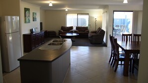 Une cuisine moderne dotée d’un îlot central, d’un coin repas avec une table et des chaises, et d’un salon avec un canapé.