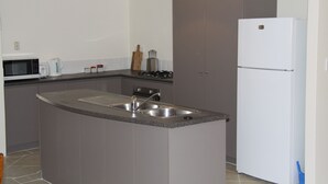 Une cuisine compacte équipée d’un évier, d’un four à micro-ondes, d’une cuisinière et d’un réfrigérateur.