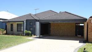 Une maison à deux étages avec une allée pavée, un garage et une façade en briques.