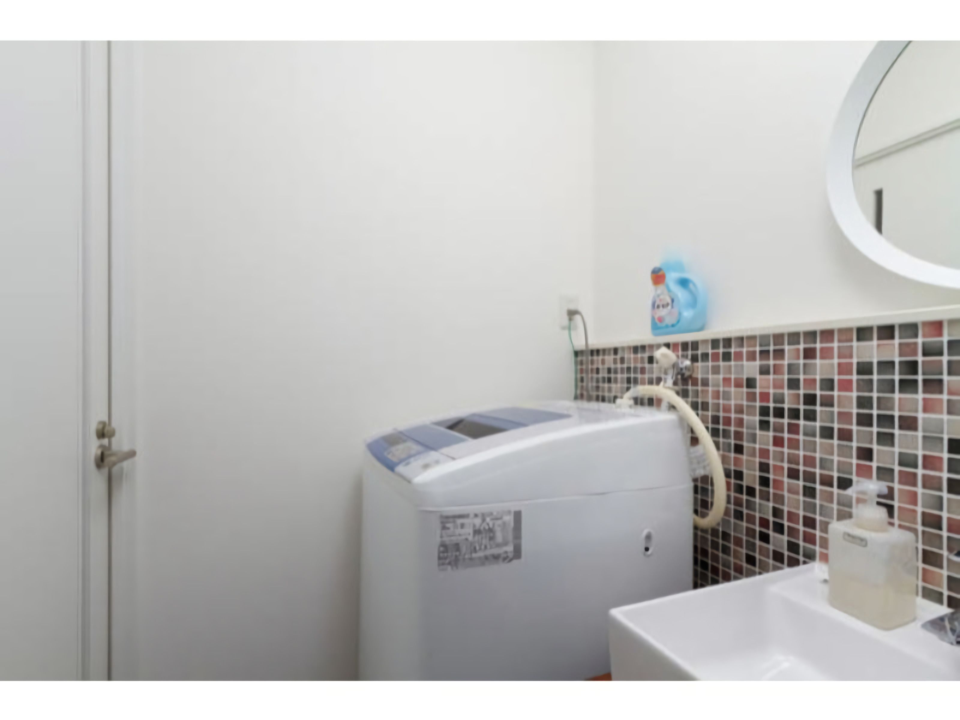 Un baño con un lavamanos blanco, un espejo y un calentador mural.