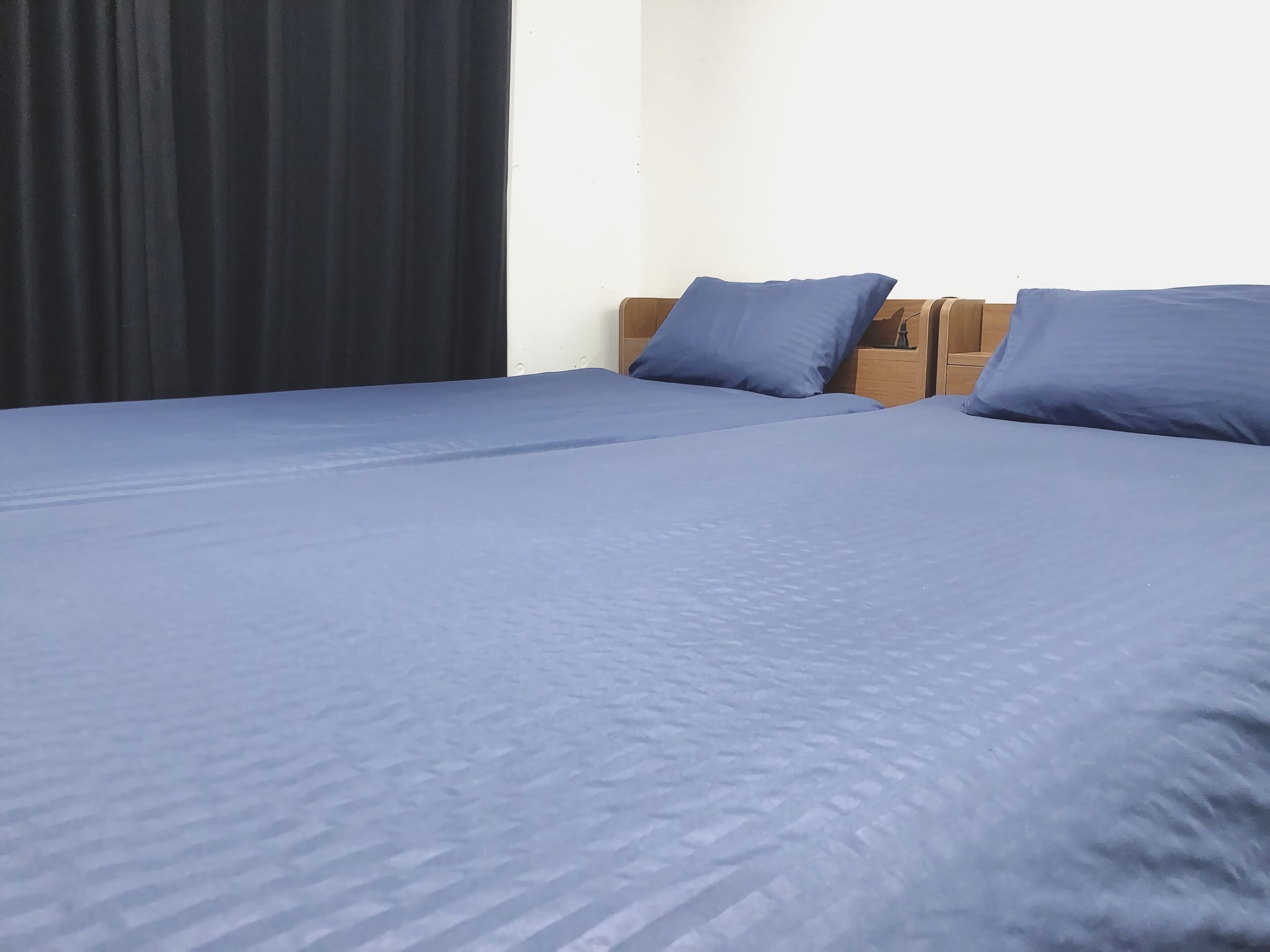 Une chambre avec deux lits, chacun recouvert d’une courtepointe bleue et agrémenté d’oreillers assortis.