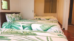 A bedroom with a bed featuring a tropical leaf pattern bedspread, a wooden headboard, and a window with a view of greenery. - The Wonder At Stay -bentencho- (Osaka)