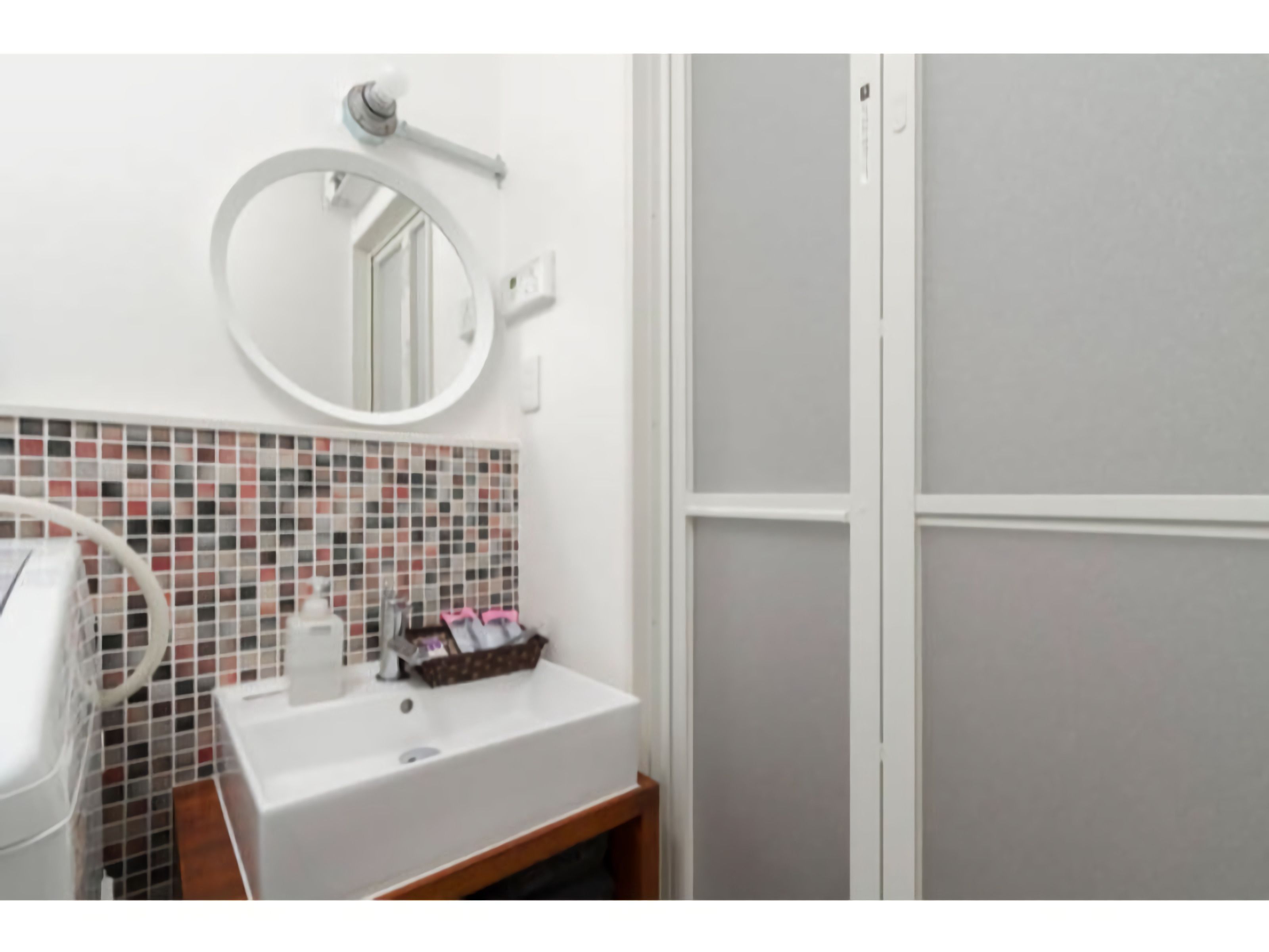 A bathroom with a white sink, a mirror, and a tiled backsplash.