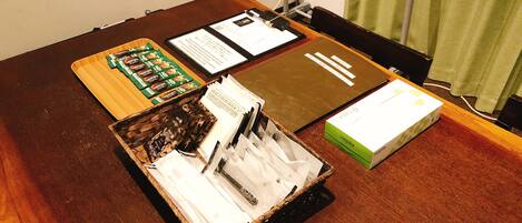 A wooden table with a clipboard, documents, a box, and a basket with items.