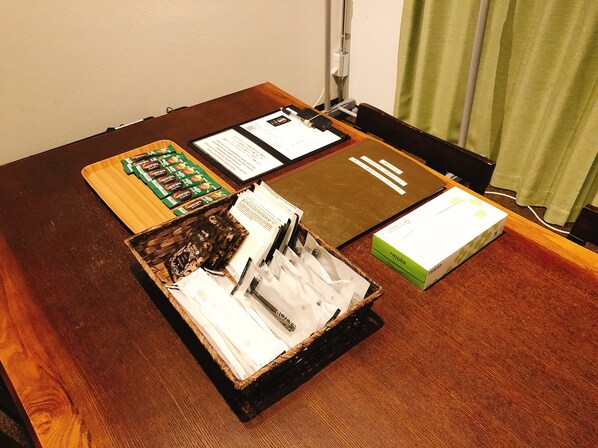 Una mesa de madera con un portapapeles, documentos, una caja y una cesta con objetos.