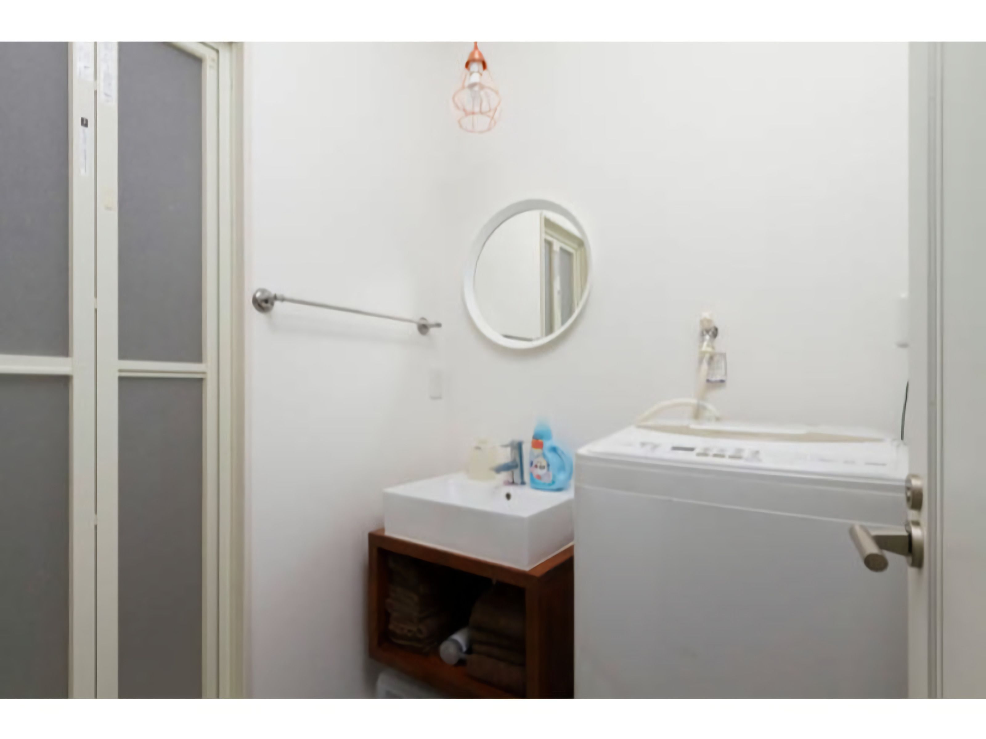 Ein Badezimmer mit einem weißen Waschbecken, einem Spiegel und einem Handtuchhalter.
