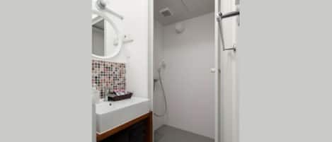 A bathroom with a white sink, a mirror, and a shower area.