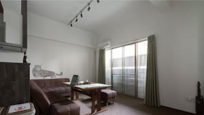 A spacious living room with a large sectional sofa, a wooden coffee table, and a laptop on a small table. There is a sliding glass door leading to a balcony. - The Wonder At Stay -bentencho- (Osaka)