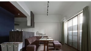 A modern living room with a sectional sofa, a dining table, and a large window with curtains. - The Wonder At Stay -bentencho- (Osaka)