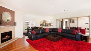 Una sala de estar moderna con chimenea, un sofá modular negro y una alfombra roja.