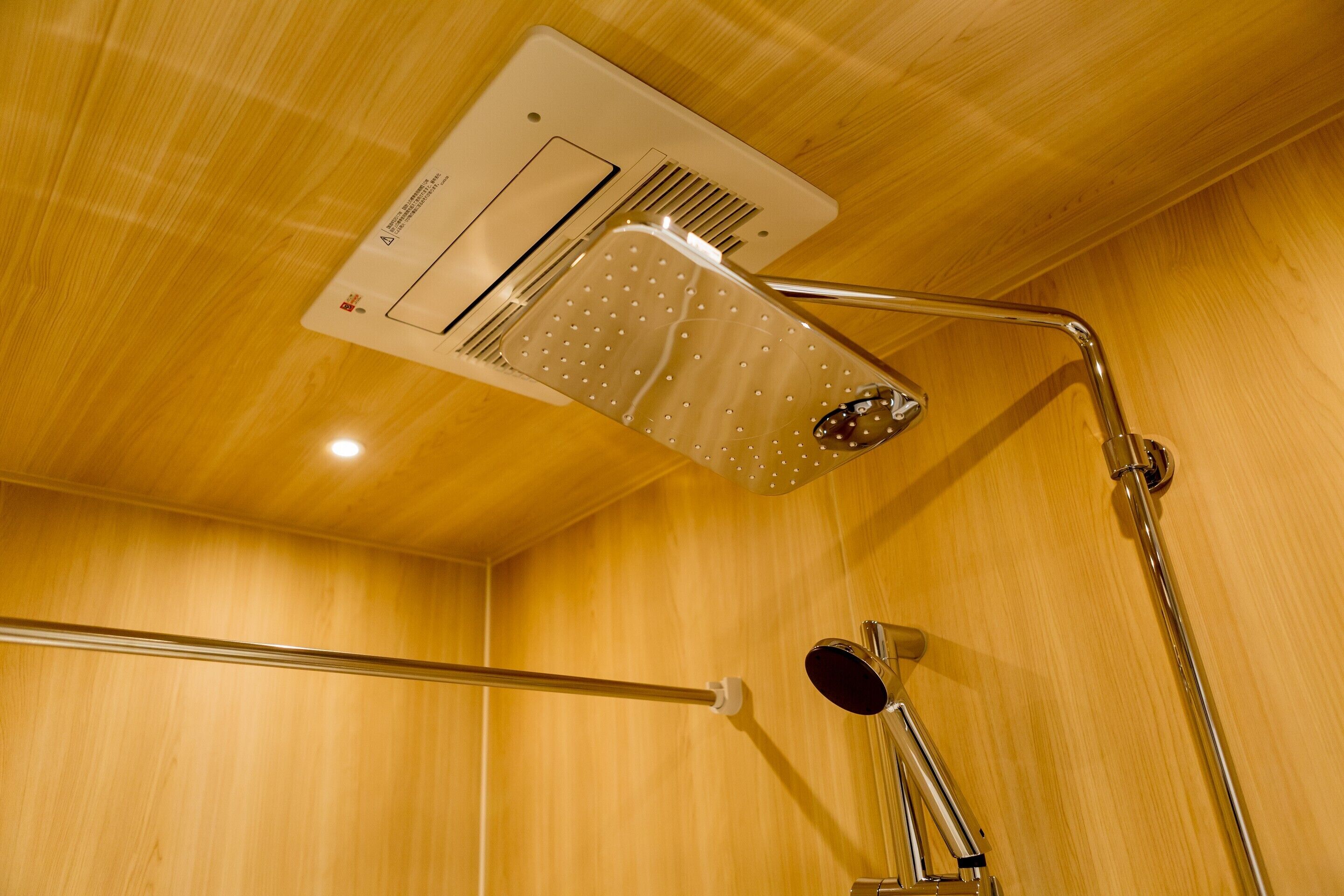 Une douche équipée d’un pommeau de douche à main et d’un panneau de commande fixé au mur.