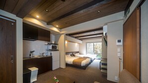 A compact hotel room with a kitchenette, two beds, a small sitting area, and a view of the outdoors. - RESI STAY Nishiki (Kyoto)