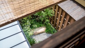 A view from a window overlooking a wooden deck with a small garden area, including a rock and greenery. - RESI STAY Nishiki (Kyoto)