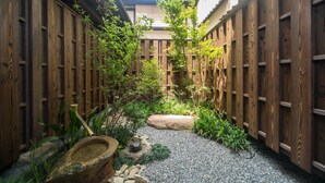 A traditional Japanese garden with wooden fences, a gravel path, and various plants. - RESI STAY Nishiki (Kyoto)