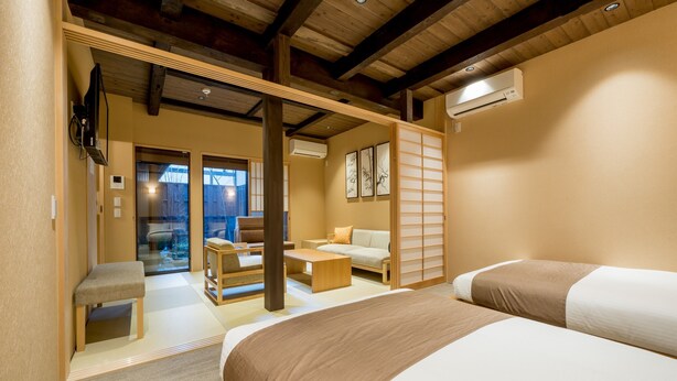 A hotel room with a large bed, a sofa, a small table, and a sliding door leading to a balcony. - RESI STAY Nishiki (Kyoto)