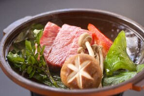 A hot pot with meat, vegetables, and mushrooms.