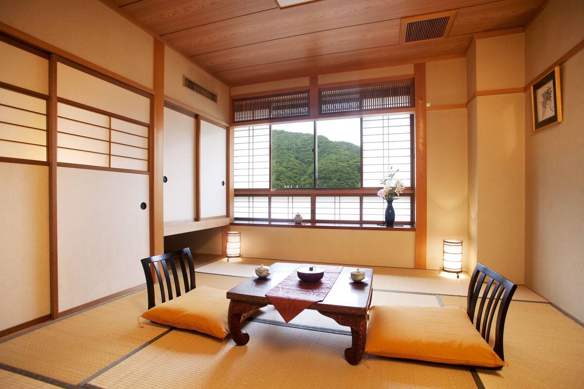 Ein traditioneller japanischer Raum mit Tatami-Boden, einem niedrigen Holztisch und Kissen.