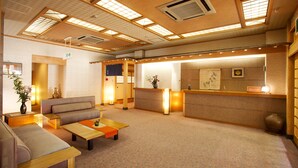 A traditional Japanese-style hotel lobby with tatami mat seating, a reception desk, and a reception area with a counter and framed artwork. - Hirayuonsen Yamatokan (Takayama)