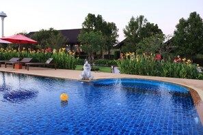 A swimming pool with a mosaic tile design, surrounded by lush greenery and a statue. - Sawasdee Sukhothai Resort (Sukhothai)