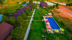 An aerial view of a resort with multiple buildings, a swimming pool, and a well-maintained lawn. - Sawasdee Sukhothai Resort (Sukhothai)
