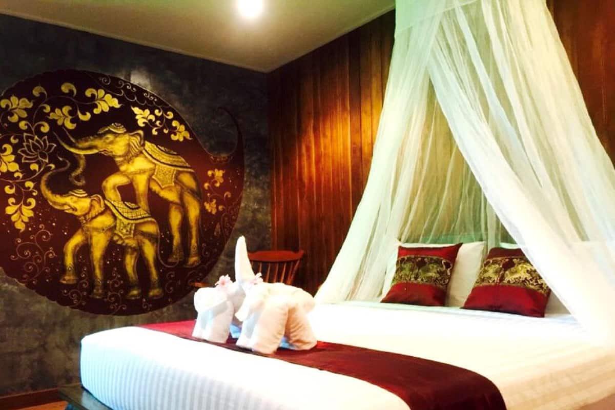 Una cama con dosel, una pared con un mural decorativo y una silla de madera.