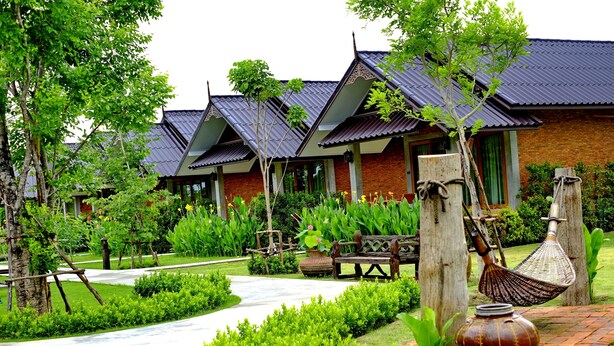 A traditional-style building with a tiled roof and brick walls, surrounded by well-maintained gardens and a paved pathway. - Sawasdee Sukhothai Resort (Sukhothai)