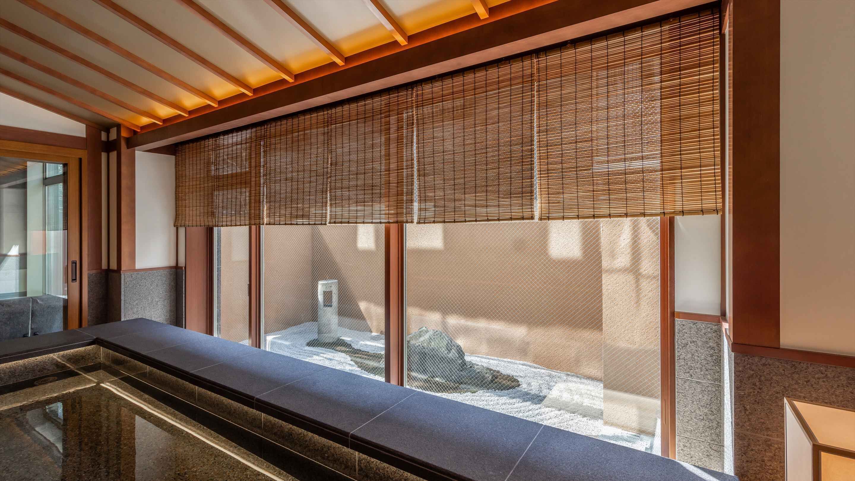 A modern interior with a stone bench, a wooden ceiling, and a view through a bamboo screen.