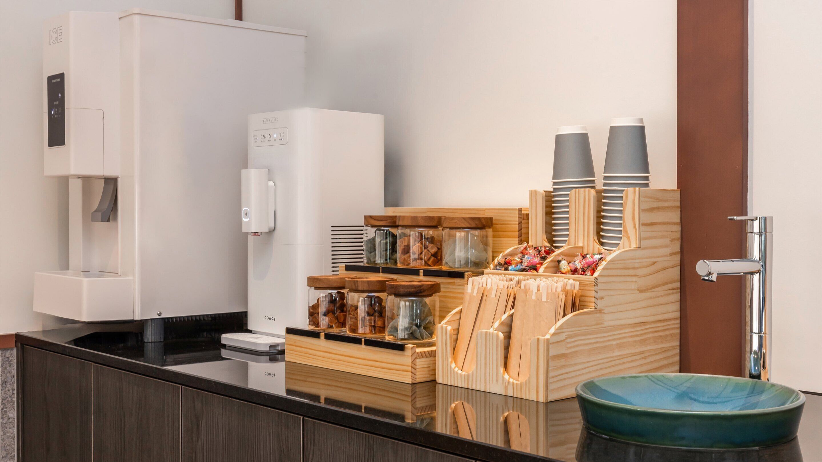 A modern kitchen with a coffee machine, a water dispenser, and a sink.