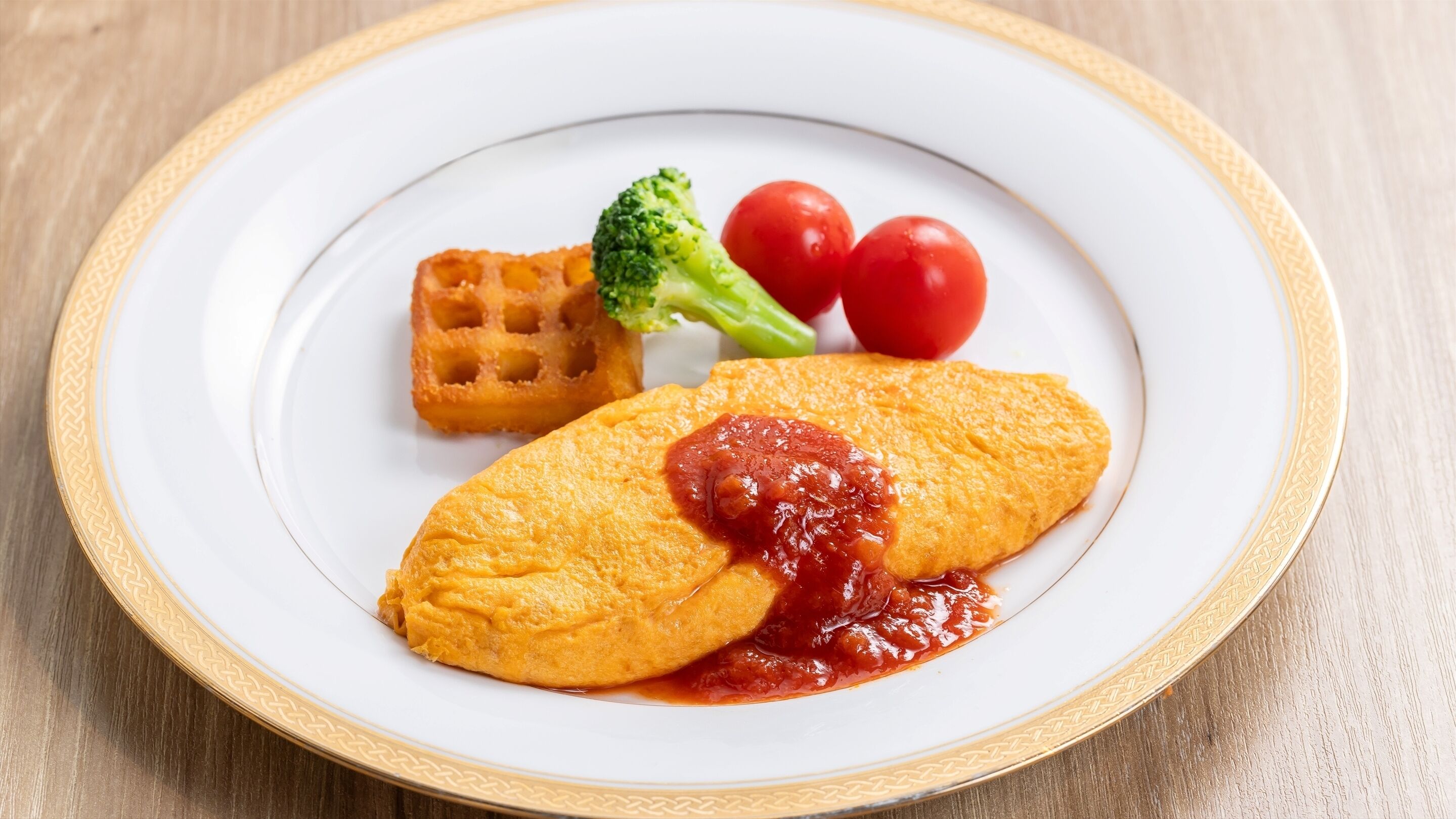 Ein Teller mit Omelett, Tomatensauce, Brokkoli und Cocktailtomaten.