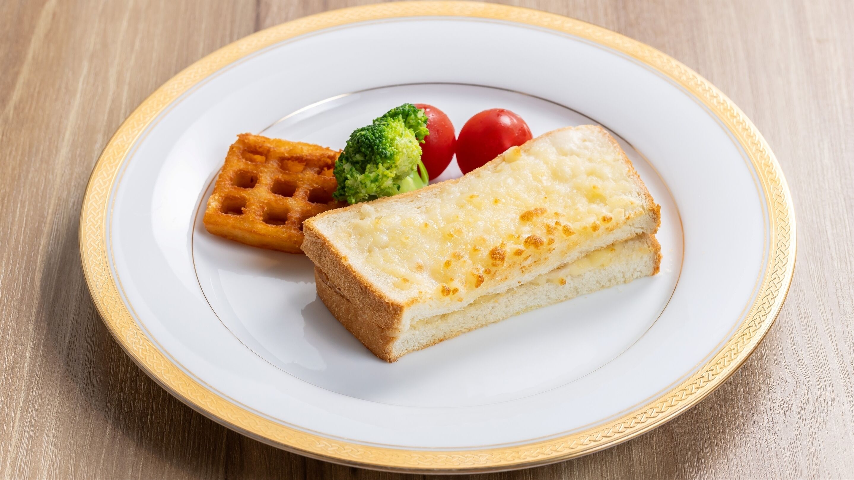 A plate with a waffle, a slice of cheese, and a piece of broccoli.