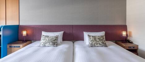 Una cama doble con dos almohadas, una mesita de noche con lámpara y un cabecero de madera.