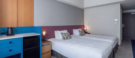 A hotel room with a bed, bedside tables, a desk with drawers, a lamp, and an air conditioning unit.