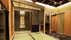 Una habitación con esteras de tatami, puertas correderas de madera y un mampara de shoji, con una estética japonesa tradicional.