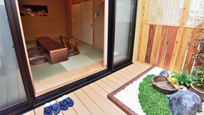 Una habitación japonesa tradicional con suelo de tatami, una mesa de madera baja y una puerta corredera que da a un espacio privado.