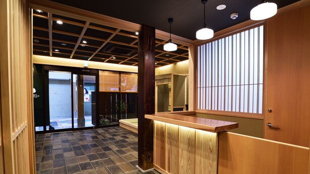 Zona de recepción con un mostrador de madera, suelo de baldosas y vistas al exterior a través de amplios puertas correderas.