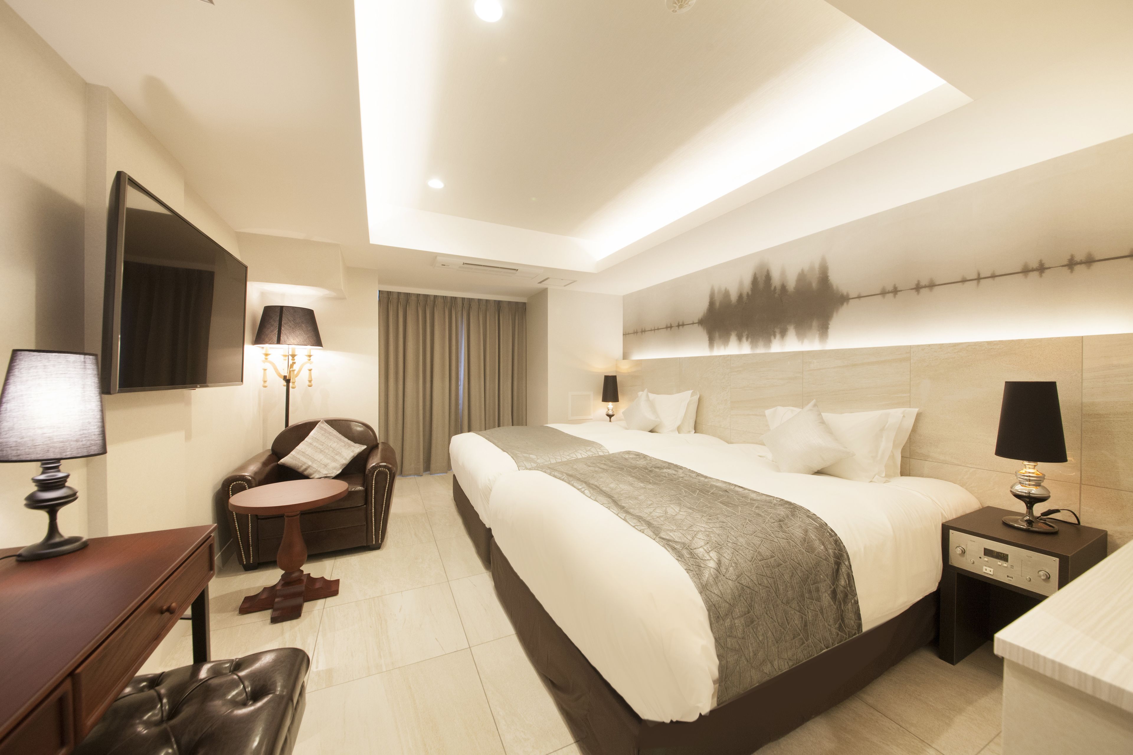 Une chambre d’hôtel moderne avec un grand lit, un bureau, une chaise et une table de chevet avec des lampes.