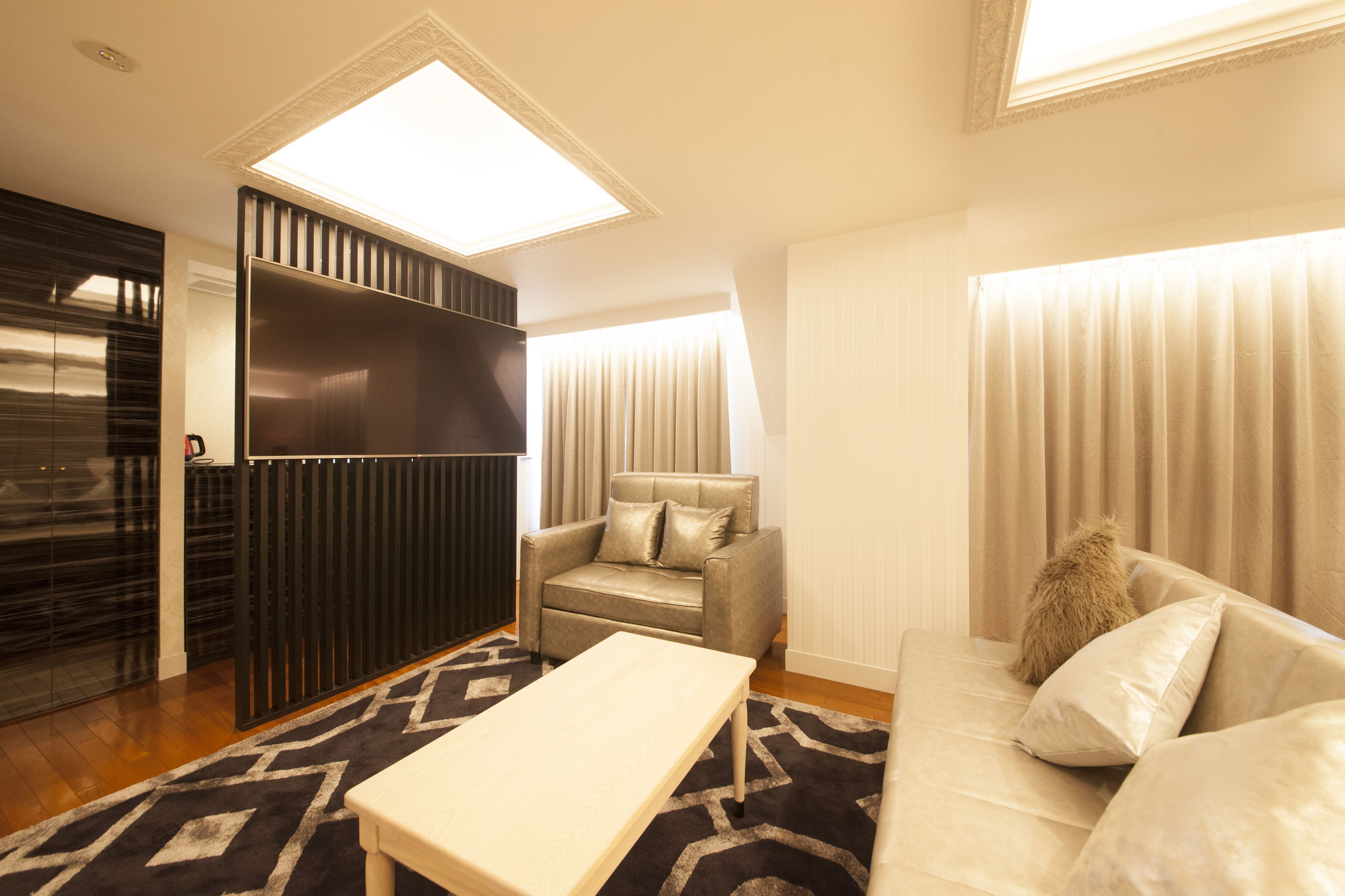 A modern living room with a sofa, a chair, a TV, and a large window.