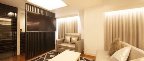 A modern living room with a sofa, a chair, a TV, and a large window.