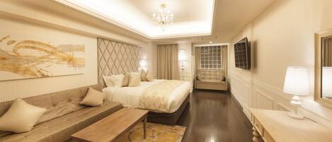 Una habitación de hotel con cama, sofá, escritorio, silla y televisor.