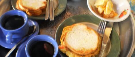 A tray with breakfast items including toast, eggs, and a bowl of fruit.