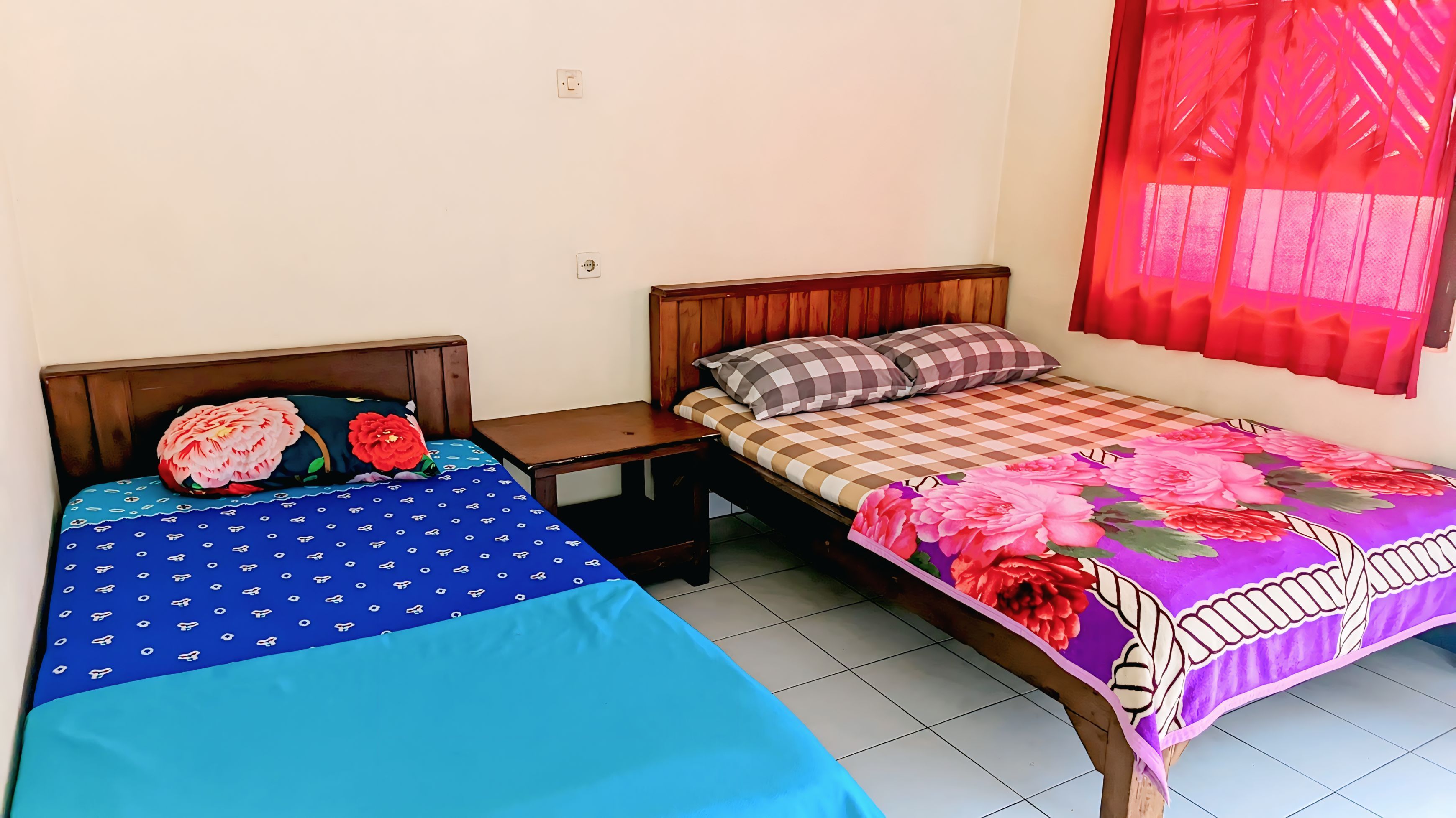 A room with two beds, each with a distinct patterned bedspread.